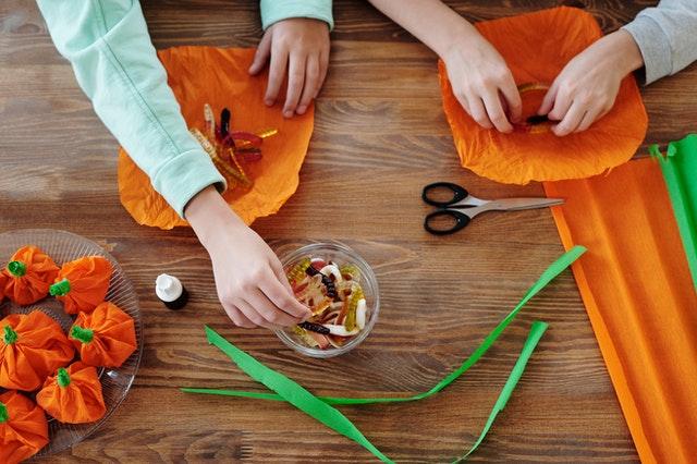 2 children putting together orange tissue paper Halloween party decorations